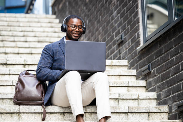 istock Man in elegant suit sitting on steps and working on laptop computer. 1727571819
