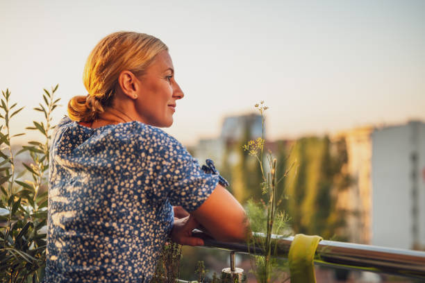 istock Woman enjoys  standing on her balcony at sunset 1727576315
