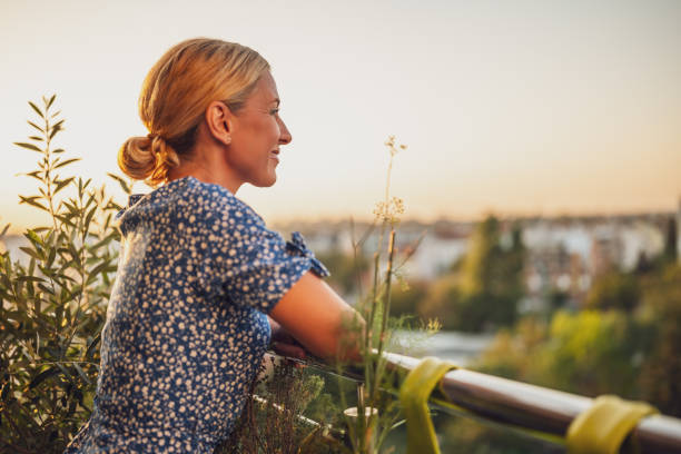 istock Woman enjoys  standing on her balcony at sunset 1727576321