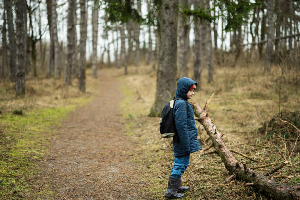 istock Boy with backpack and rain boots in the forest. 1727579129