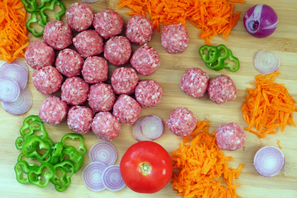 Meatballs in sweet and sour tomato sauce in the pan. Wooden background