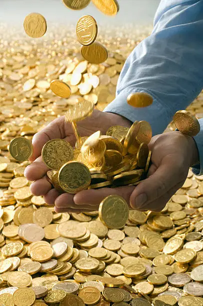 Goldcoins raining into hands of a businessman