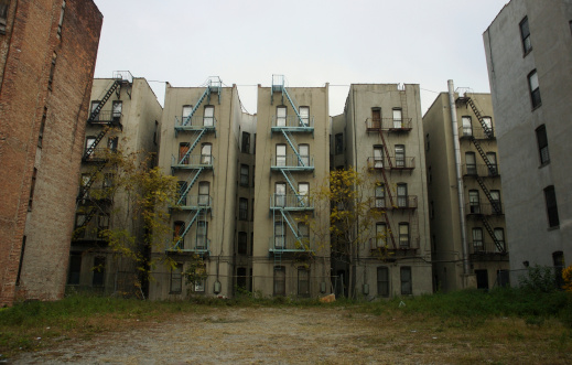 Grim view of a drab apartment row over an empty lot on a gray day