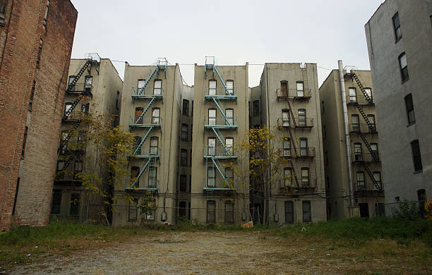 Inner City Tenement Apartment Buildings Sometimes Called Ghetto Grim view of a drab apartment row over an empty lot on a gray day run down neighborhood stock pictures, royalty-free photos & images