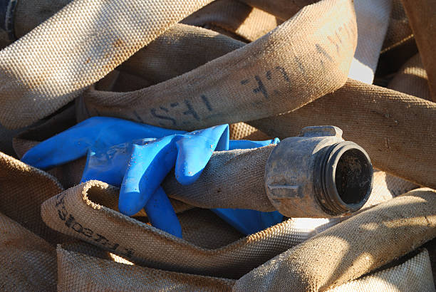 un tuyau pression en toile, avec une paire de gants en caoutchouc bleu - tube messy dirty stack photos et images de collection