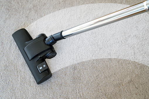Vacuum cleaner cleaning a streak on a carpet to eliminate dirt and allergy causing house dust mites, copy space, selected focus, narrow depth of field