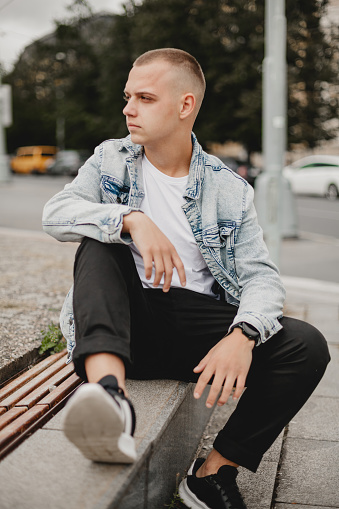 Urban Contemplation. Young Man in Denim Jacket Deep in Thought. City Musing. Brooding Young Guy in Stylish Denim Jacket. Thoughtful Urbanite. Young Man Reflecting in His Denim Jacket.