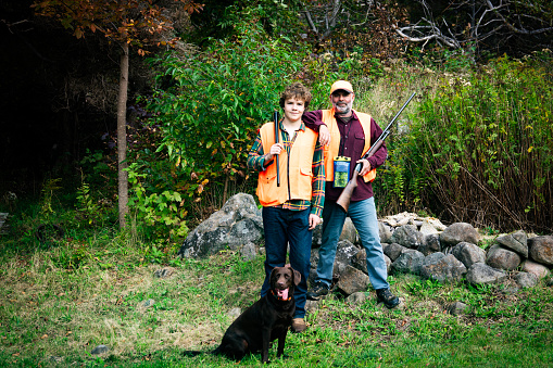A father and son with their Labrador Retriever out grouse hunting on a fall day