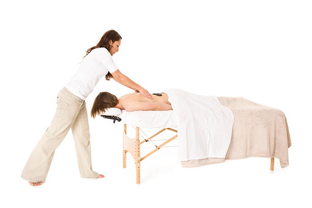 Hot Stone Massage Photo of a masseuse giving a hot stone massage. massage table stock pictures, royalty-free photos & images