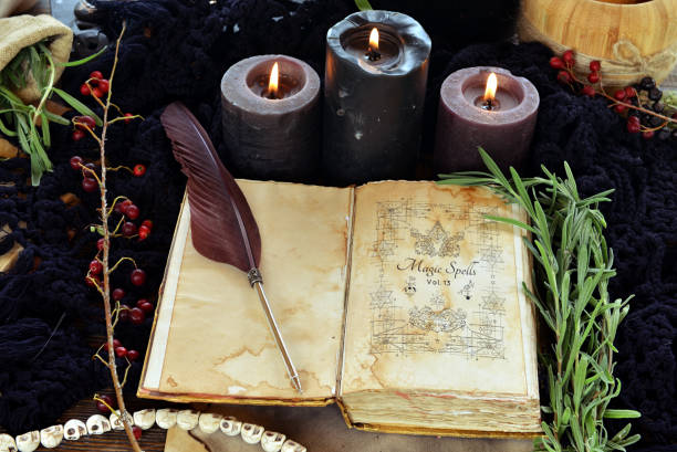 istock Witch book of spells with black candles on altar table. Occult, esoteric and divination still life. Mystic Halloween background with vintage objects for magic ritual 1727628354