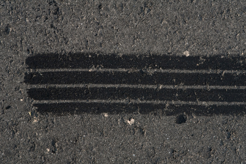 Tire track on weathered asphalt.