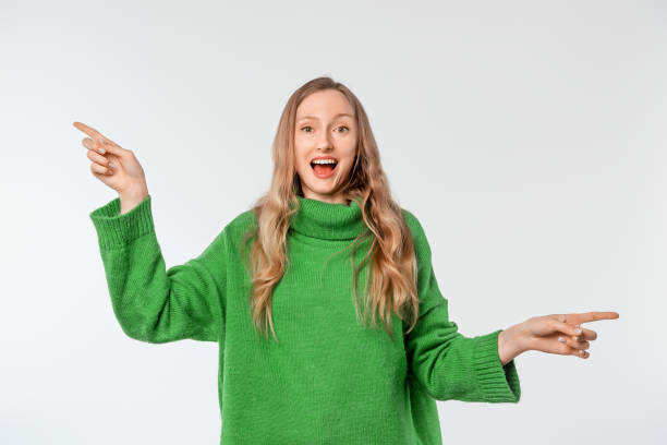 istock Enthusiastic young blonde woman pointing pointing sideways, left and right direction, clueless what to choose, making decision, wearing green cozy sweater, standing over white background 1727639354