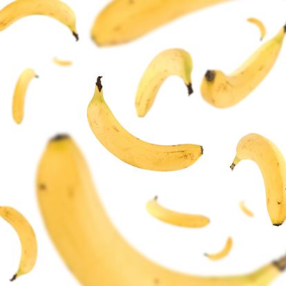 Many bananas in a freefall on white background.