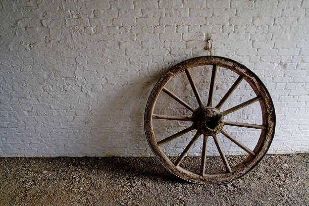 white brick wall with antique wooden wheel stock photo