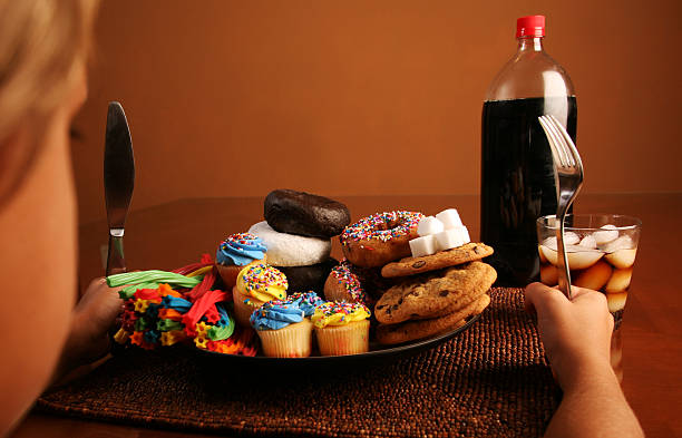 Dziecko z płyta pełna cukru, pączki, cukierki i napoje gazowane – zdjęcie