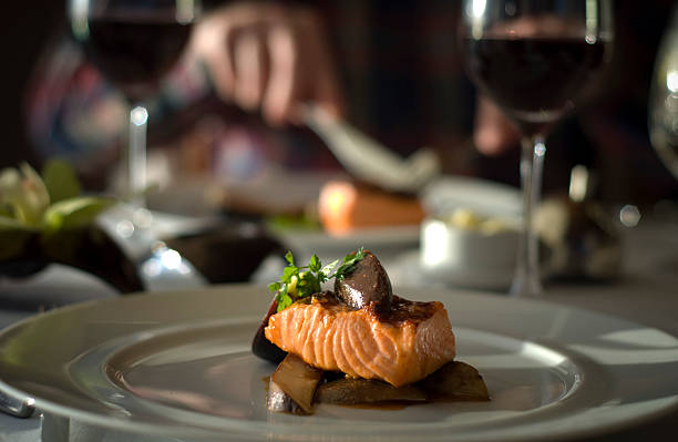 dîner raffiné & table romantique pour deux, du restaurant salmon dîner de fruits de mer - wine red wine prepared fish prepared potato photos et images de collection