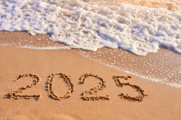 2025 year written on sandy beach sea at sunny day