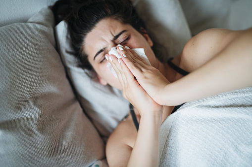 Young woman struggling with cold and flu and a runny nose.