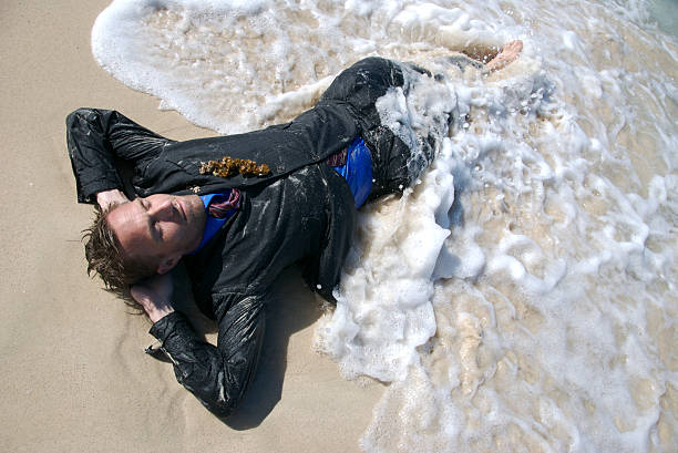 relaxado homem de negócios em terno deitado na praia com ondas - stranded beached beach businessman imagens e fotografias de stock