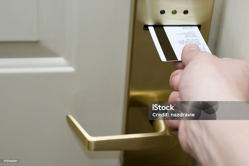Hand Inserting Hotel Room Electronic Door Lock Keycard Male hand inserting a magnetic strip keycard into a electronic hotel door lock to unlock the door.  Hotel Stock Photo
