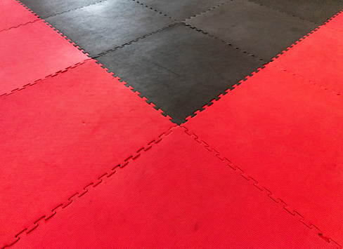 Black and red Muay Thai tatami, worn from countless training sessions.