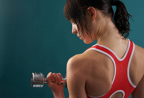 Young woman in workout wear holding a dumbbell weight stock photo