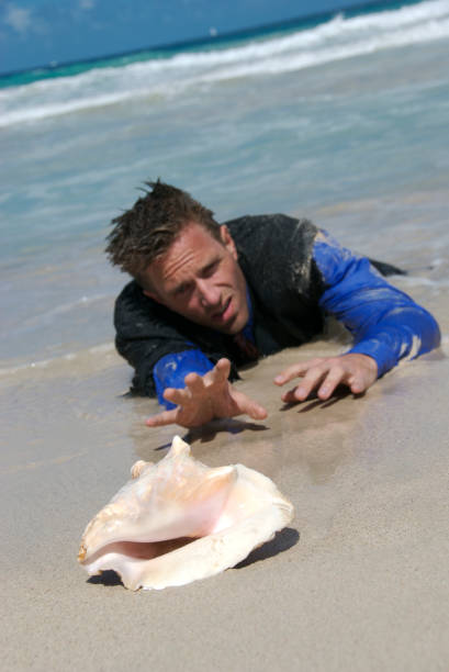 naufrago uomo d'affari raggiunge per il guscio telefono - stranded beached beach businessman foto e immagini stock