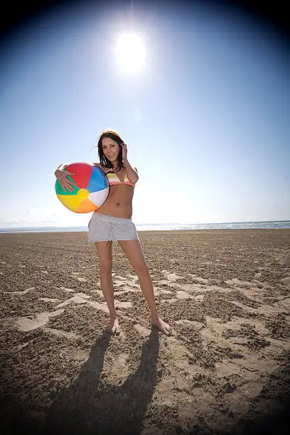 "young woman holding a beachball at the beach, vignette intentional"