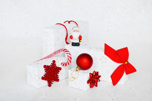 Christmas gift composition. White and red winter decorations on white background. Christmas,  new year concept. Presents with boxes, ribbon and ball. Front view. Card, calendar and advent concept.