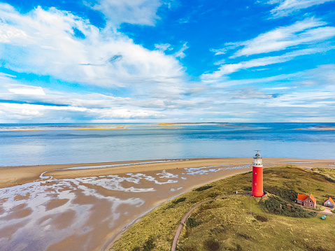 Lighthouse at the Wadden island Texel in the dunes during a calm autumn afternoon. Drone view over the lighthouse, dunes and the North Sea beach. The Eierland lighthouse is located at the North point of the island.