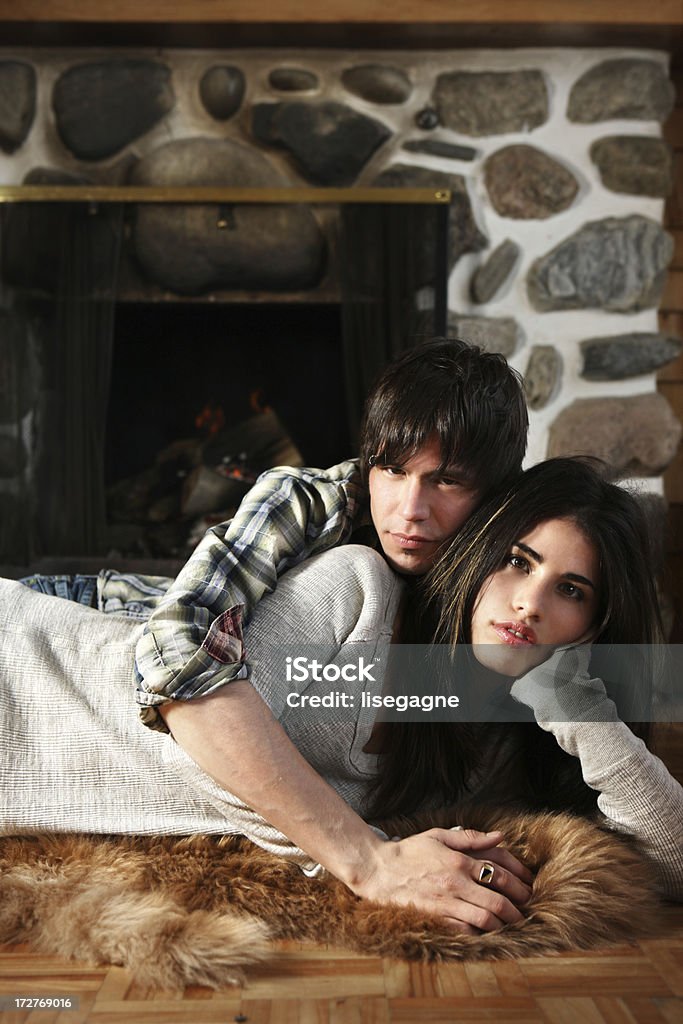 Joven hombre y mujer sentada frente a la chimenea - Foto de stock de Abrazar libre de derechos