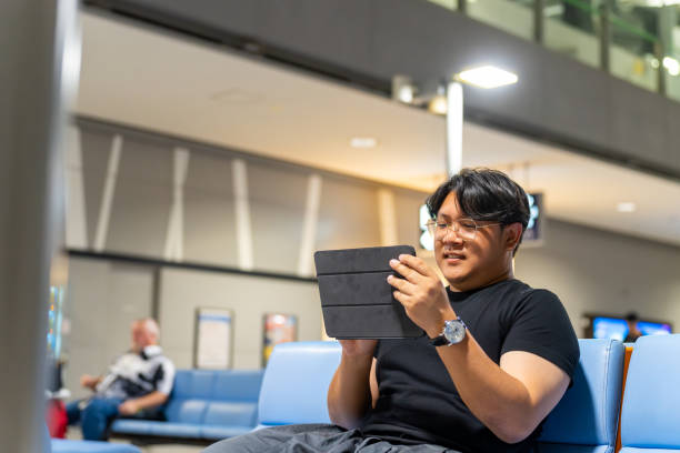 istock Asian man using digital tablet at airport terminal. 1727690404