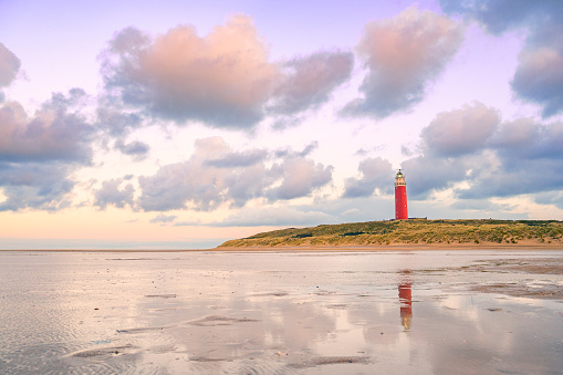 Lighthouse at the Wadden island Texel in the dunes during a calm autumn evening with reflections on the North Sea beach. The Eierland lighthouse is located at the North point of the island.