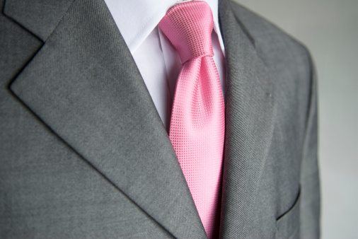 Business close-up bright pink necktie makes a colorful contrast to a neutral gray suit on businessman