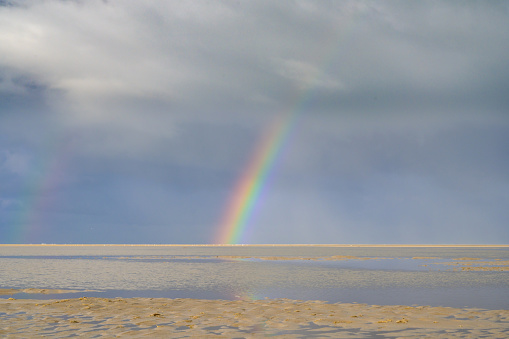 Rainbow at the beach on Texel island in the Wadden sea region in the North of The Netherlands during a stormy autumn morning.