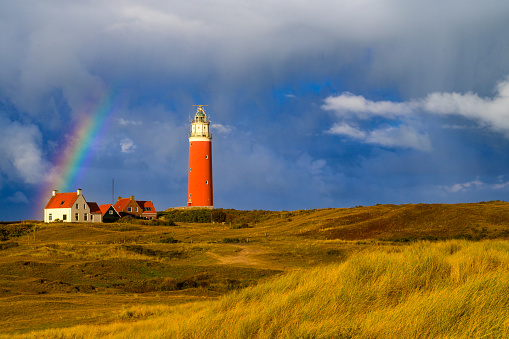 Lighthouse at the Wadden island Texel in the dunes with a rainbow during a stormy autumn morning. The Eierland lighthouse is located at the North point of the island.