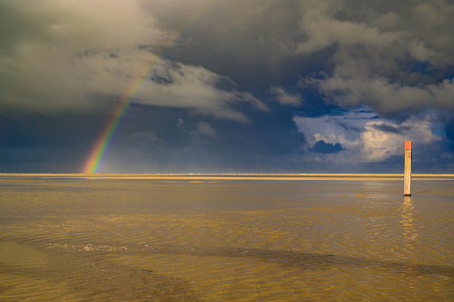 Rainbow at the beach on Texel island in the Wadden sea region in the North of The Netherlands during a stormy autumn morning.