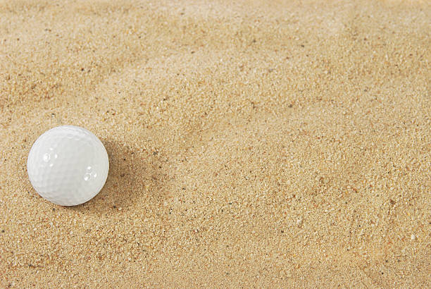 Golf ball in sand trap stock photo