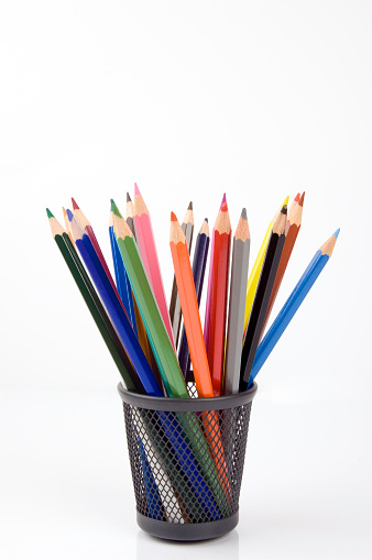 bunch of pencils in a small basket against white.