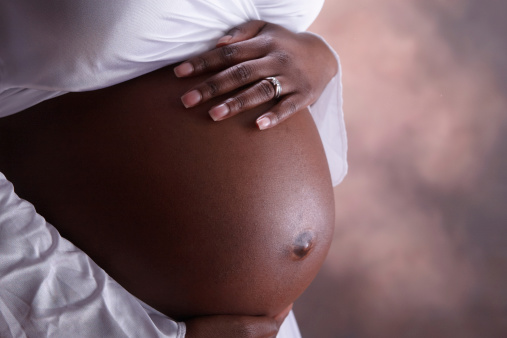 A closeup of a black woman's pregnant belly. This woman is seven months along. Shot with Canon 1D Mark III.