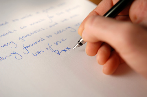 shallow depth of field image of caucasian hand holding fountain pen writing a letter