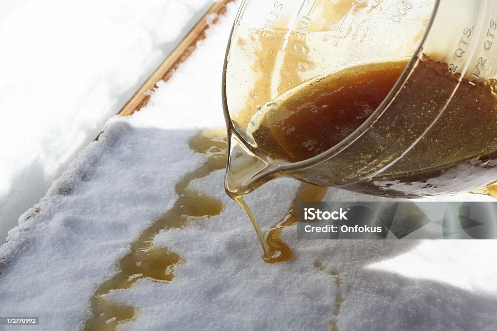 Maple Sugar Taffy on Snow at Sugar Shack DSLR picture of hot Maple sugar on snow at a sugar shack. A jar full of maple sugar is pouring the golden liquid on freshly compacted snow.  Maple Tree Stock Photo