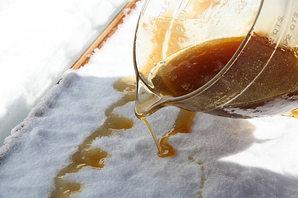 Maple Sugar Taffy on Snow at Sugar Shack DSLR picture of hot Maple sugar on snow at a sugar shack. A jar full of maple sugar is pouring the golden liquid on freshly compacted snow.  date syrup stock pictures, royalty-free photos & images