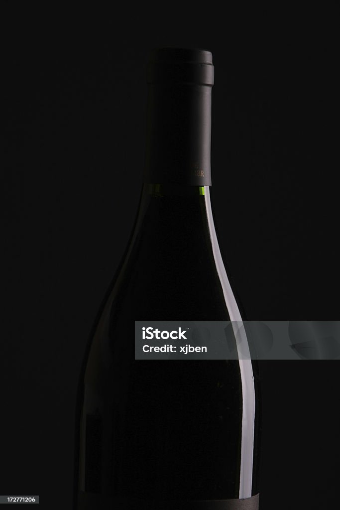 Wine Bottle Over Black Red wine bottle set against black background with only the bottle shape visible. Black Background Stock Photo