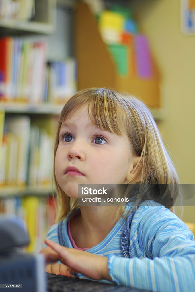 Bambina utilizzando un computer nella biblioteca - Foto stock royalty-free di Attrezzatura informatica