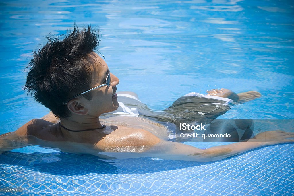 Asiatico bel giovane uomo galleggiando su schiena, Blu piscina, Copyspace - Foto stock royalty-free di A petto nudo