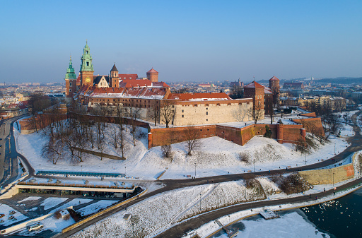 Kraków, Poland – March 1, 2018: Wawel Castle, Cathedral and partly frozen Vistula river in winter. Aerial skyline in sunset light