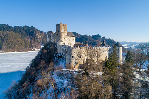 Niedzica, Poland - February 14, 2022:  Medieval castle in Niedzica, dating back to 14th century (upper castle) in winter. Frozen artificial Czorsztyn lake on Dunajec river