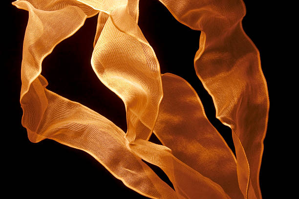 Golden orange ribbons twist and bend upwards in an abstract background.