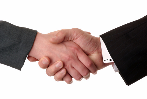 Businessman shaking hands with a businesswoman.  The man has the ace of spades up his sleeve, representing an advantage.  Isolated on white.